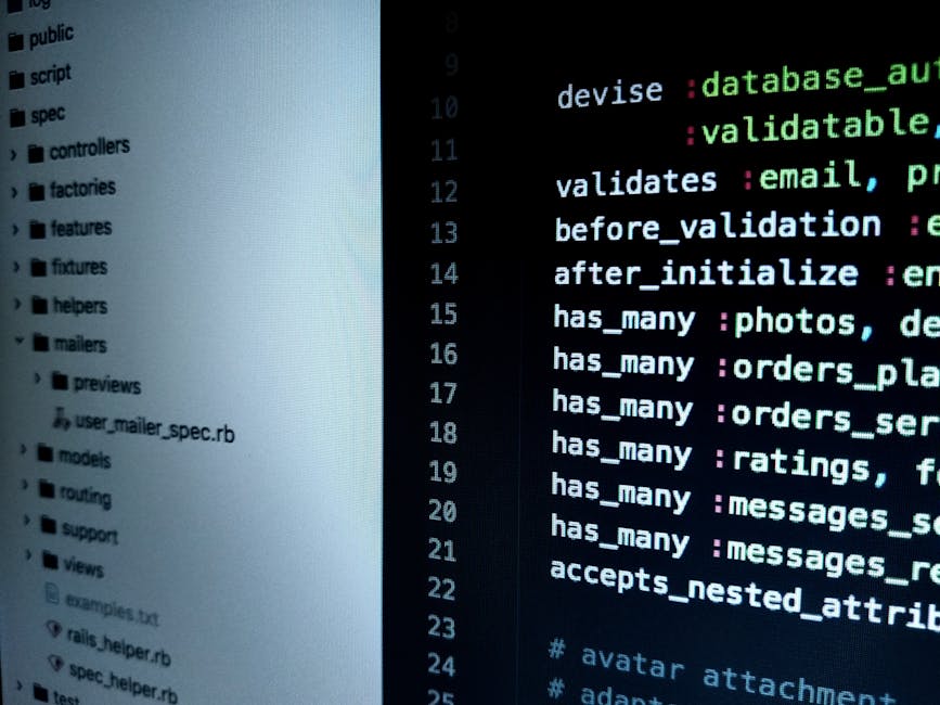A person's right hand, wearing a wristwatch, is positioned on the keyboard of a laptop placed on a wooden surface. The laptop screen displays lines of programming code with a dark background and brigh